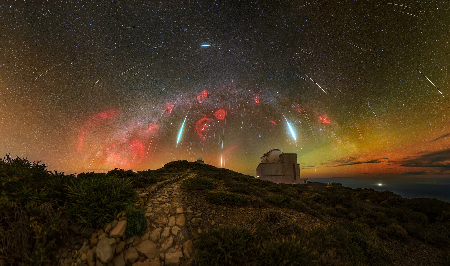 the meteor looks like a shower with a red glow of light visible above the building 