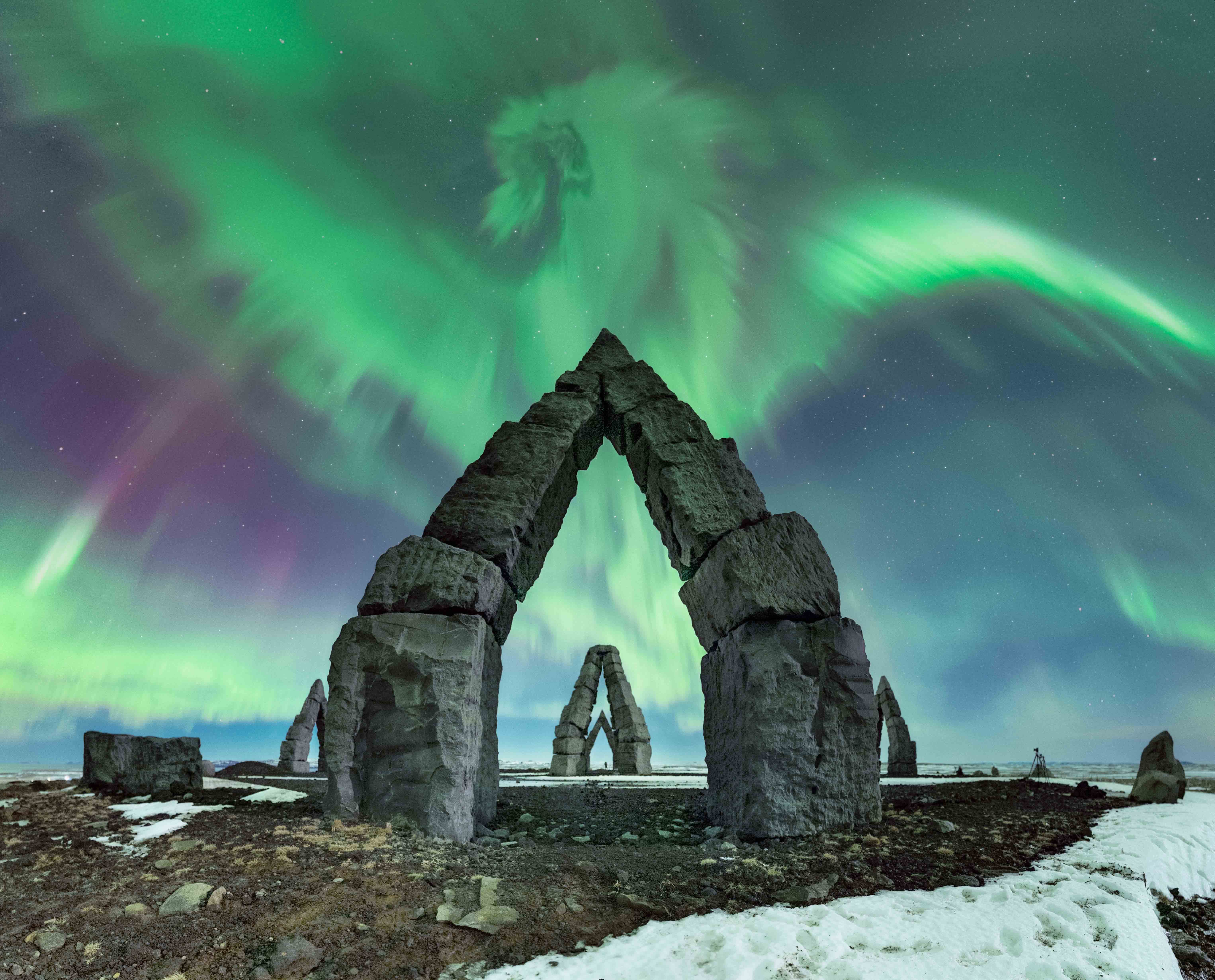 green and purple aurora over Vs-shaped stone structures