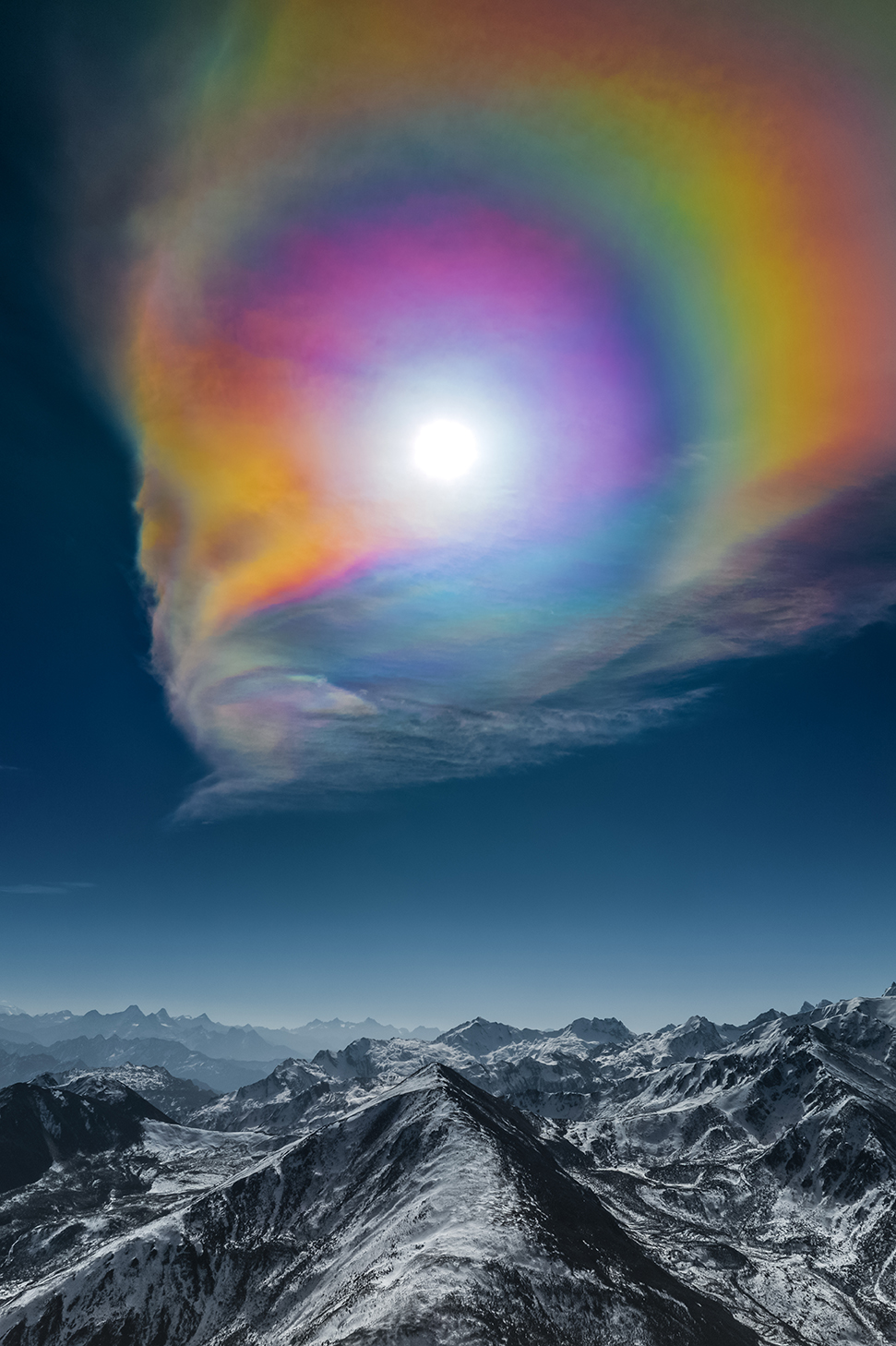 a rainbow appears around the sun above the mountains 