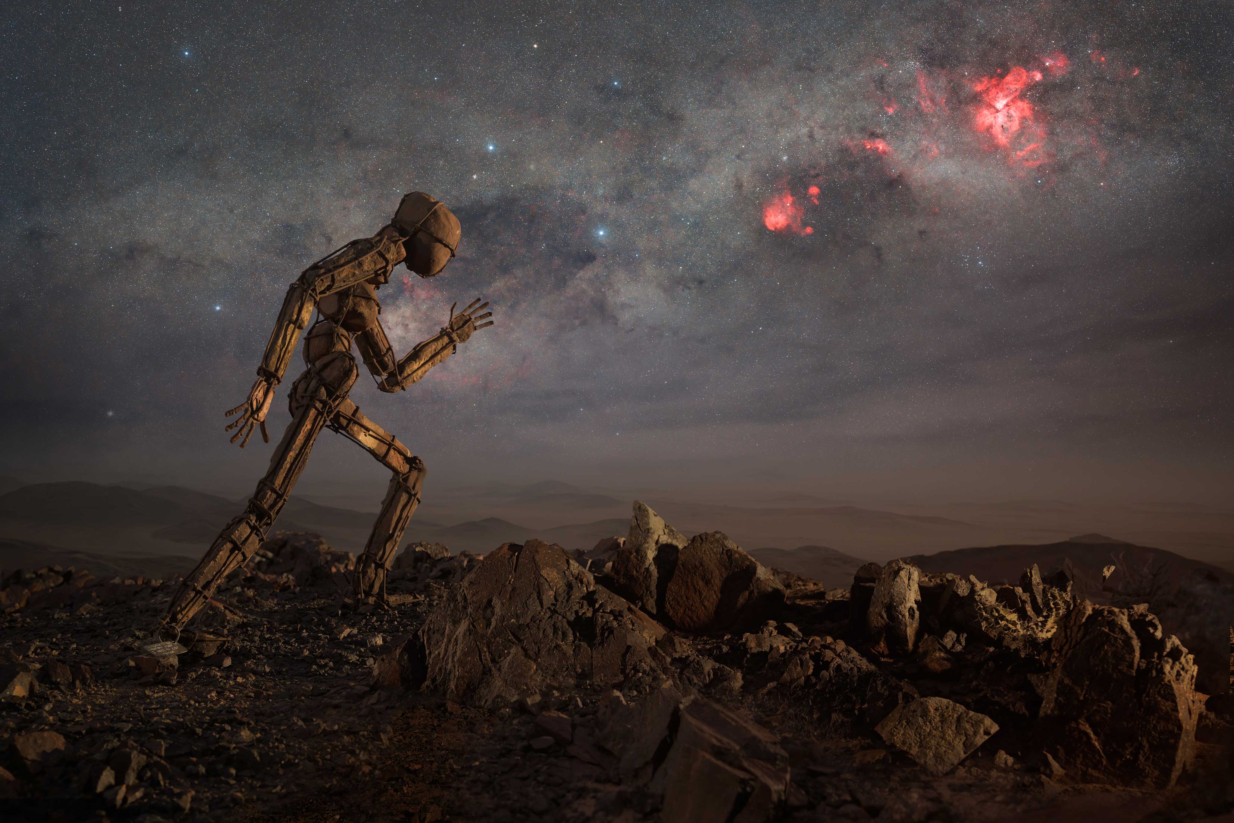 statue of a man walking under the milky way