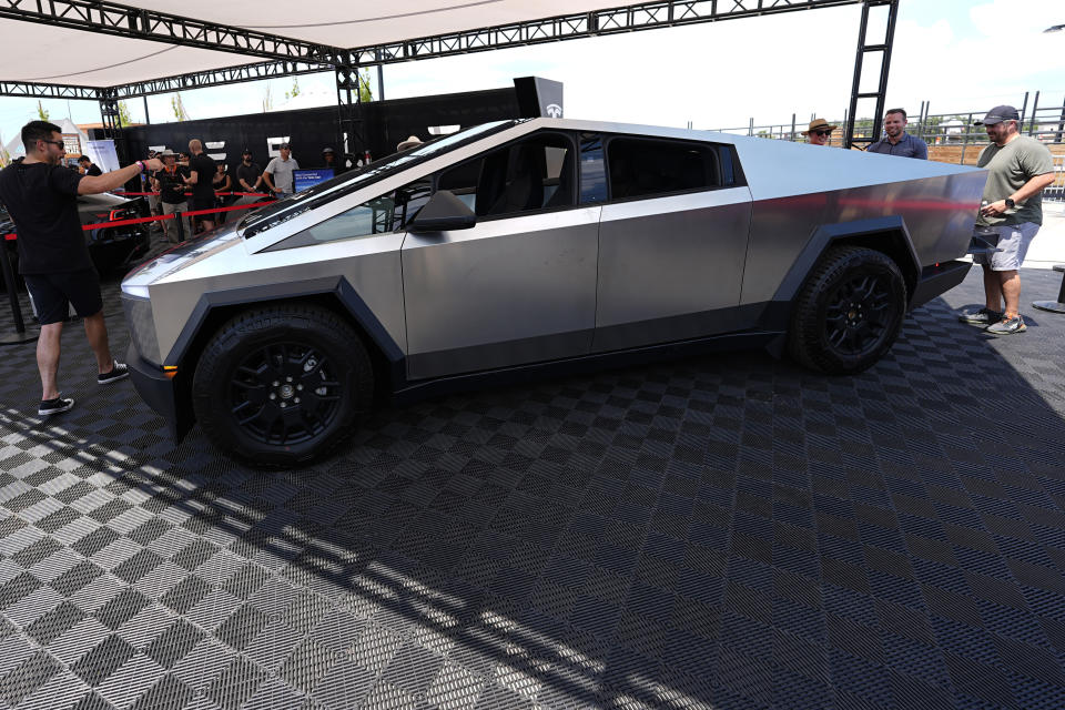 Visitors look at the 2024 Cybertruck at Tesla's display at the Electrify Expo, Sunday, July 14, 2024, north of Denver.  The show was making its first stop in Denver as part of a nationwide effort to showcase the latest in a wide range of electric vehicles from cars and trucks to bicycles and even skateboards. .  (AP Photo/David Zalubowski)