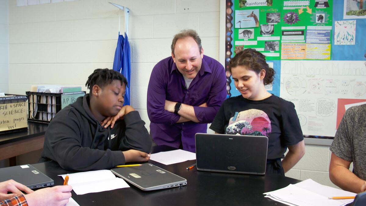 Ben Kravitz, assistant professor of earth and space science at Indiana University, chats with high school students DeWayne Murphy and Emerald Yee during class at Bloomington High School South.